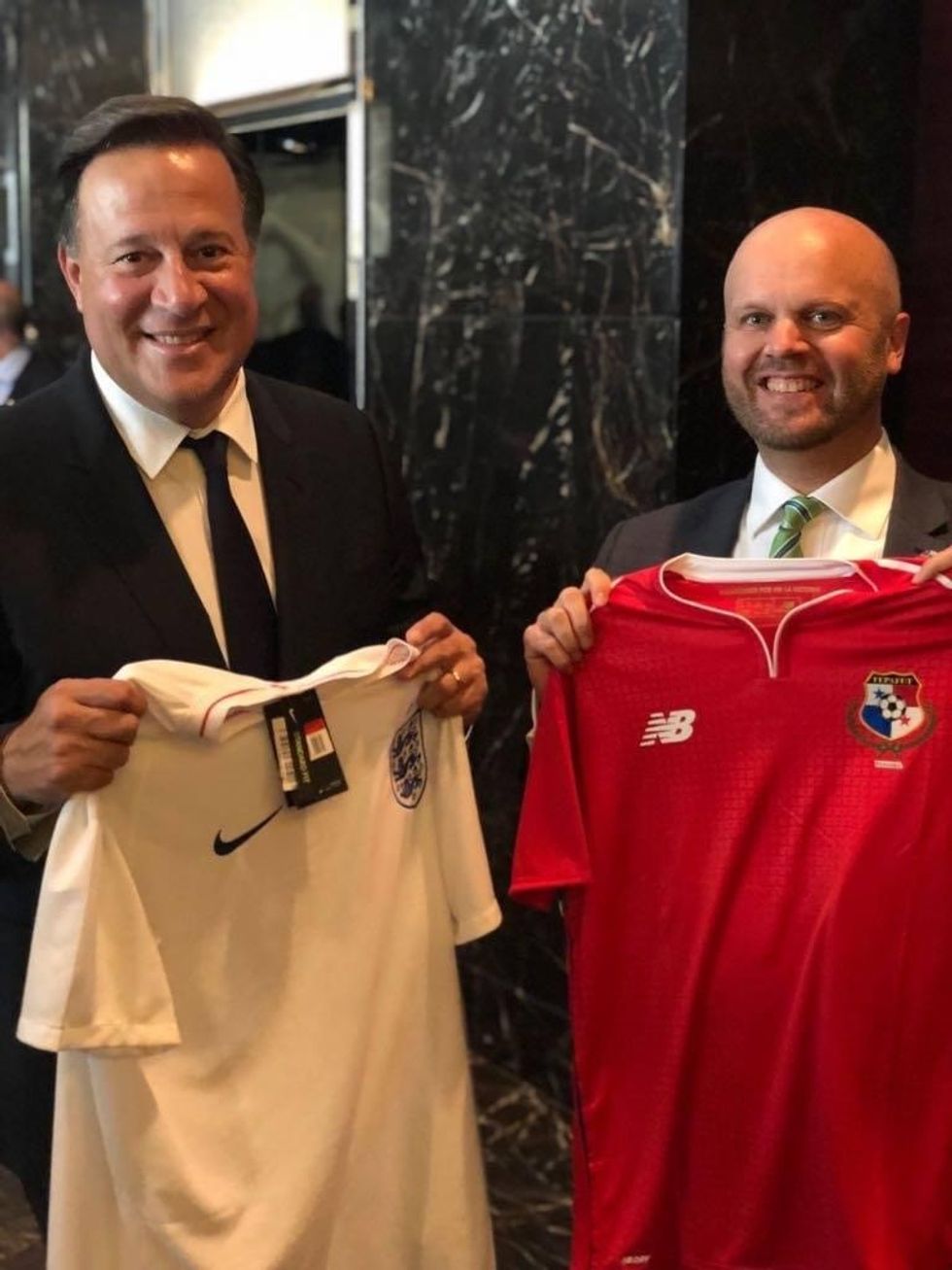 El ex diplomático británico Damion Potter posa con el presidente panameño sosteniendo las camisetas de Panamá e Inglaterra